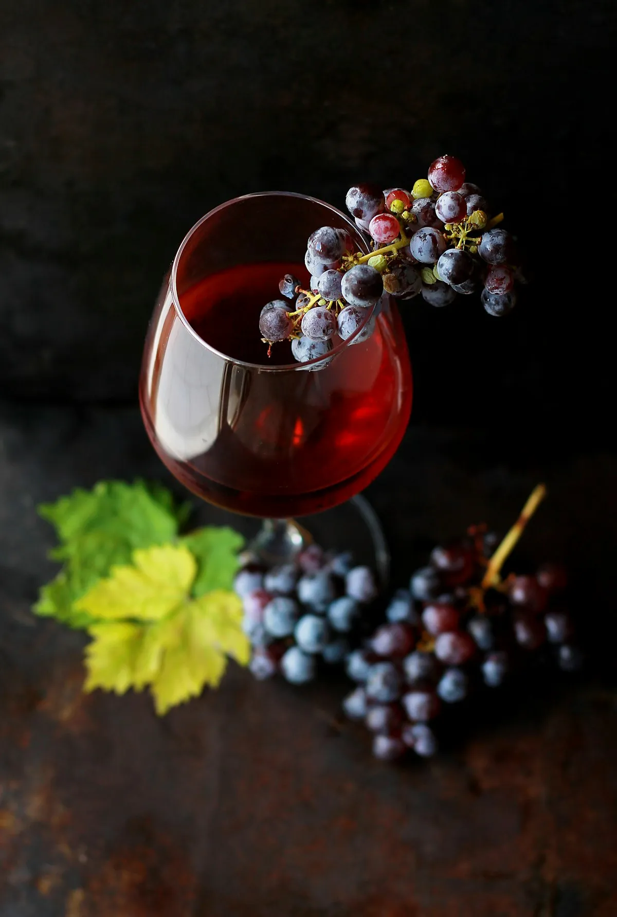 Calice di vino rosso con grappolo di uva del podere